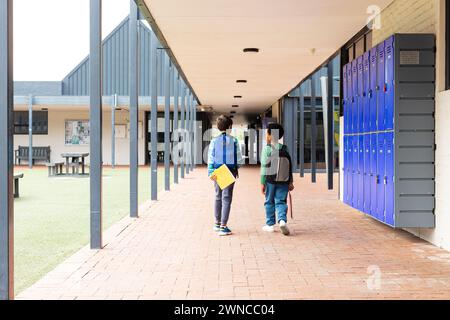 Biracial boy and African American boy walk down a school corridor Stock Photo