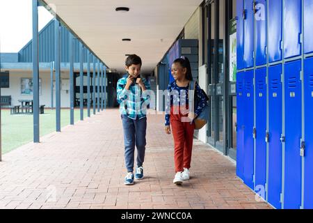 Biracial boy with a red plaid shirt and backpack smiles in a school ...