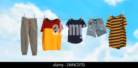 Different clothes drying on washing line against blue sky, banner design Stock Photo