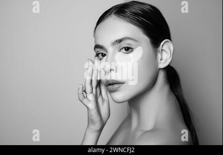 Beauty girl face with flakes under the eyes. Womans flakes. Patches under close eyes for woman. Young girl with patches under eyes from wrinkles. Stock Photo