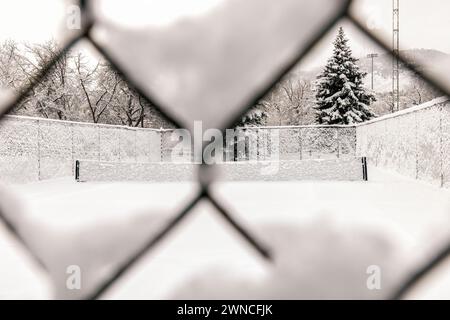 View of snow-covered tennis courts through fence. - Golden, Colorado, USA Stock Photo