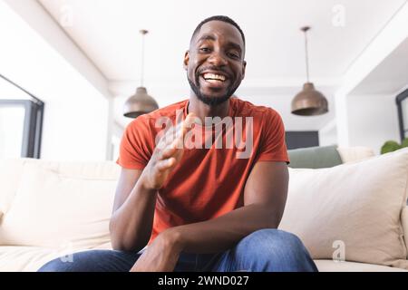 African American man in a red shirt is smiling and clapping on a video call Stock Photo