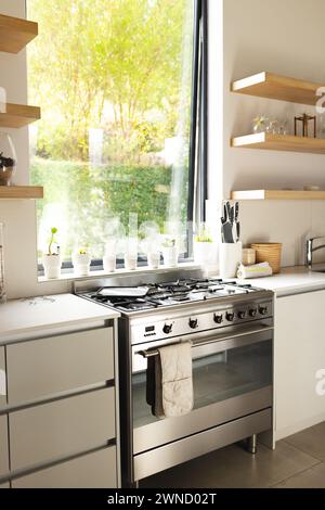 A modern kitchen features a stainless steel stove and white countertops with copy space Stock Photo