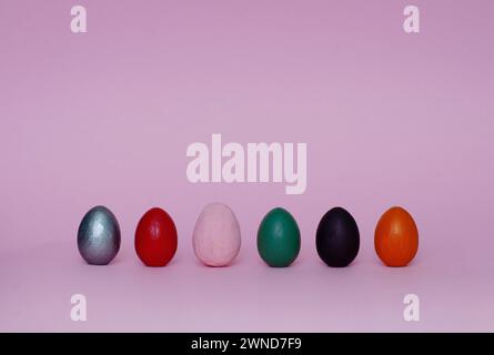 Six assorted ornamental hand painted eggs stand on paper background. Easter composition. Stock Photo