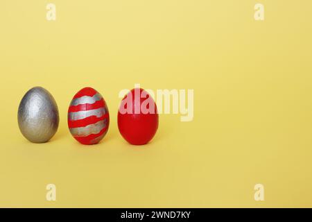 Three multi-colored decorative freshly painted eggs on a yellow background. Colored easter eggs on a light background Stock Photo