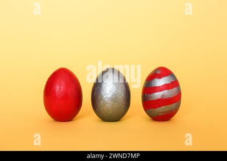 Three multi-colored decorative freshly painted eggs on a yellow background. Colored easter eggs on a light background Stock Photo