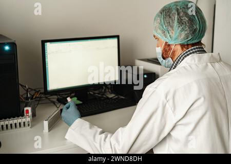 Medical scientist in uniform working on personal computer in research laboratory Stock Photo