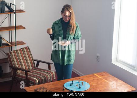 A purposeful woman stands next to the coffee table and looks intently at the chess pieces on the blue circle. Psychological training. Step-by-step ana Stock Photo