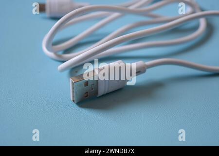 White folded usb and micro usb cable on blue background. Stock Photo