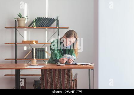 A young pretty lady speaks thoughtfully and intently on the phone while counting money. Stock Photo