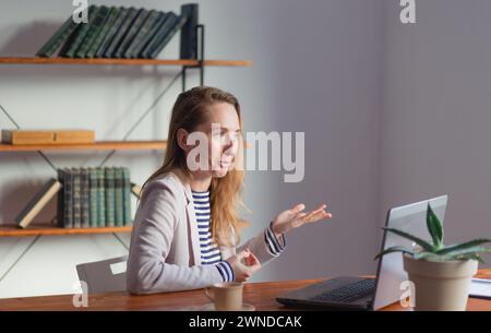 A young pretty businesswoman communicates via video conference on a laptop. Stock Photo