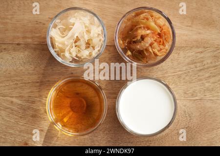 Fermented foods in glass bowls - kimchi, sauerkraut, apple cider vinegar and kefir, top view Stock Photo