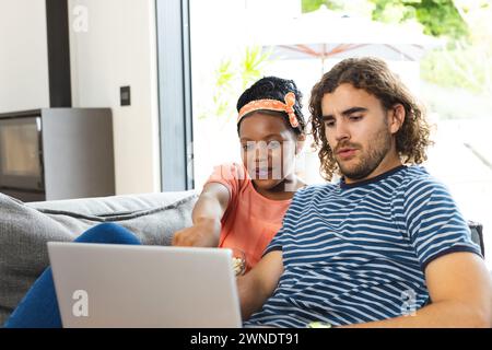 Diverse couple young African American woman and Caucasian man sit together with a laptop Stock Photo
