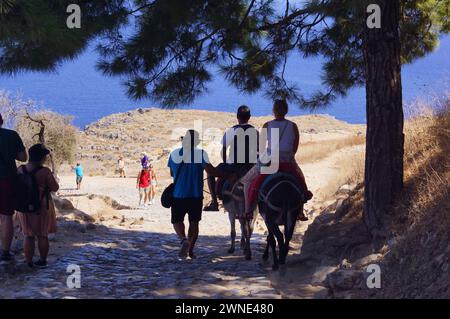 A couple of tourists riding donkeys down the acropolis of Lindos, Rhodes (Greece) Stock Photo