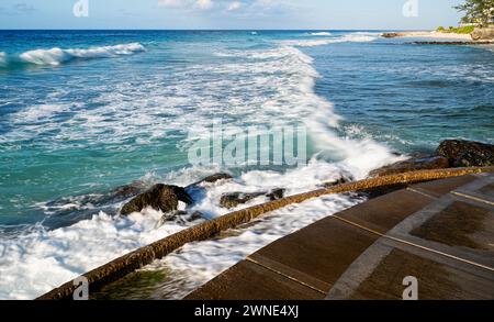 Inviting crystal clear sea and foaming surf gently lapping on the beautiful soft sands of Rockley Beach, Barbados. Stock Photo