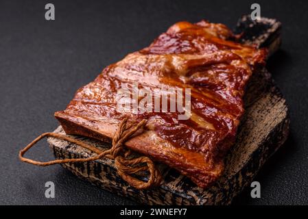 Delicious smoked or grilled ribs with olives, spices and herbs on a dark concrete background Stock Photo