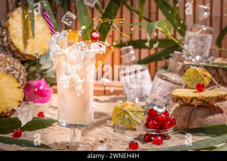 Falling ice cube cubes create splashing cream in a tropical cocktail surrounded by fruit, sand and gin bottles Stock Photo