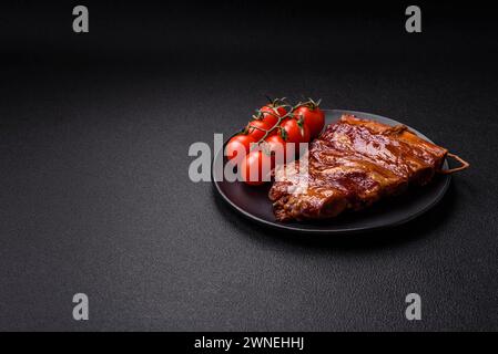 Delicious smoked or grilled ribs with olives, spices and herbs on a dark concrete background Stock Photo