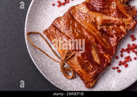 Delicious smoked or grilled ribs with olives, spices and herbs on a dark concrete background Stock Photo