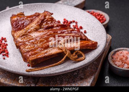 Delicious smoked or grilled ribs with olives, spices and herbs on a dark concrete background Stock Photo