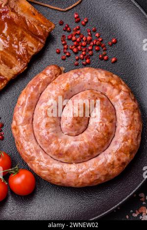 Delicious grilled sausage in the form of a ring with salt, spices and herbs on a dark concrete background Stock Photo