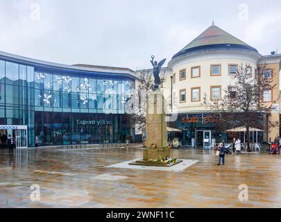 Jubilee Square, war memorial and the entrance to the Peacocks shopping centre in Victoria Place in Woking town centre, Surrey, on a dull, wet day Stock Photo