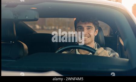 Caucasian handsome smiling man businessman sit inside modern electric car driving automobile in city road trip travel happy joyful male owner driver Stock Photo
