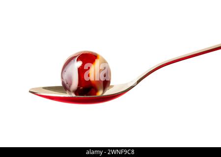 A red glass swirl marble in a spoon. Stock Photo