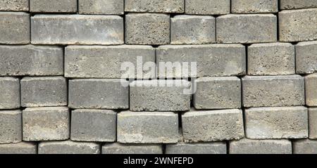 The surface of a wall or fence lined with gray bricks. Paving slabs of grey blocks of flat shape. Pavement blocks in city park. Park way materials Stock Photo
