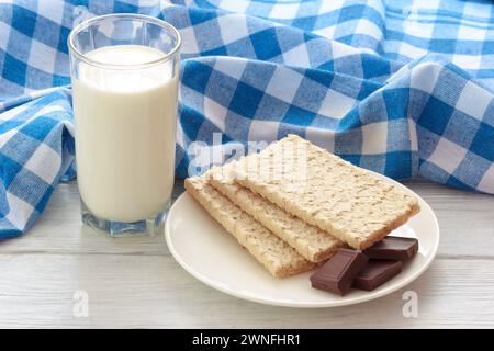 The Glass Of Fresh Milk With Oatmeal Breads And Bitter Chocolate On Plate. The Dietary Foods On Table With Blue Tablecloth. Stock Photo