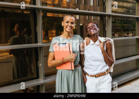 Portrait of two businesswomen standing happily facing the camera, side by side. Stock Photo