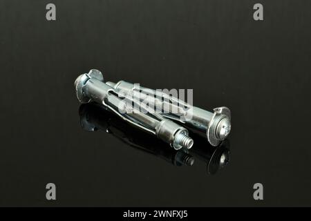 Several pieces of anchor dowels, silver, close-up, lie on a dark background. Stock Photo