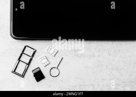 smartphone and open slots for nano SIM cards, two nano SIM cards, micro SD drive and metal key with copy space, black and white photo Stock Photo