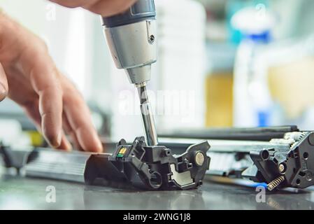 hands repairing laser toner cartridge, screw removal Stock Photo