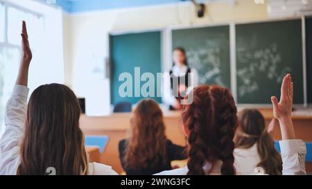 Girl students raise their hands in math class. Stock Photo