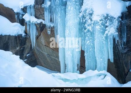 Huge blue-colored icicles on a rock wall Stock Photo