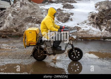 Moscow, Russia. 2nd of March, 2024. Courier of popular food delivery services 'Yandex Eda' deliveryes an order in Moscow city, Russia Stock Photo