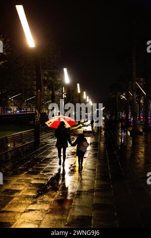MOTHER AND DAUGHTER, UMBRELLA, FANS,  BARCELONA FC, 2019: A mother and daughter walk hand-in-hand under an umbrella at night. Soaked Barcelona fans head home an easy win over a title rival in torrential rain. Photo: Rob Watkins. Barcelona FC played Sevilla FC at Camp Nou, Barcelona on 5 April 2017 and Barca won the game 3-0 with three goals in the first 33 minutes. The entire game was played in the deluge of massive spring rainstorm. Stock Photo