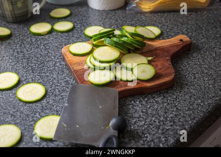 Chopped courgette slices on a wooden cutting board. Stock Photo