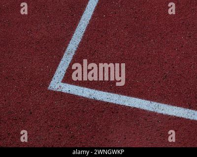 Courtside contrast. Red floor and white lines outdoor basketball court. Stock Photo