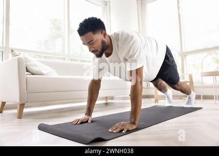Focused athletic strong African man doing pushups, morning exercises Stock Photo