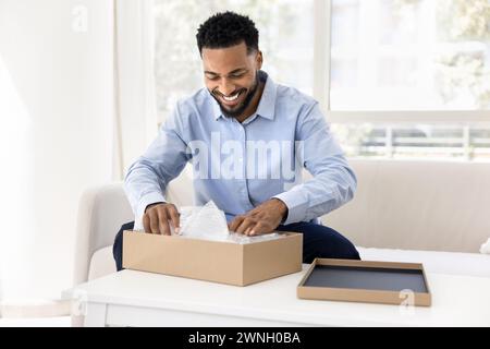 Cheerful young African consumer man getting parcel Stock Photo