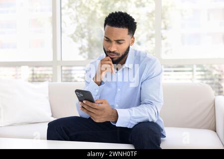Serious thoughtful young African man using financial service Stock Photo