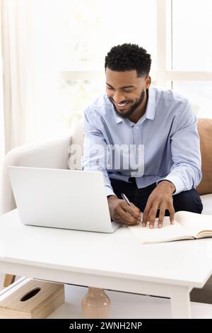 Cheerful young Black student guy watching online training lecture Stock Photo