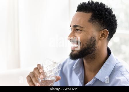 Cheerful handsome African American man drinking clear water Stock Photo