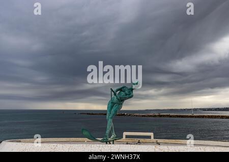 Marbella, "La Venus" una escultura de bronce que representa a una mujer practicando esquí acuático. El mar al fondo y el cielo tormentoso. España Stock Photo