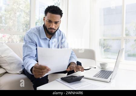 Serious young African American man calculating expenses Stock Photo