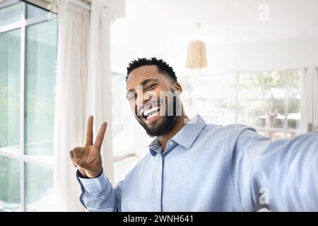 Happy joyful African American guy showing victory winner fingers sign Stock Photo
