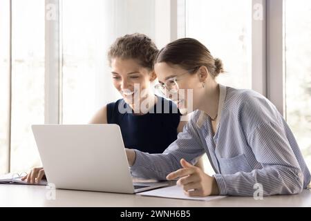 Two happy women colleagues, talking, working together on collaborative project Stock Photo