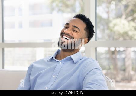 Cheerful handsome young African man sitting on white couch Stock Photo